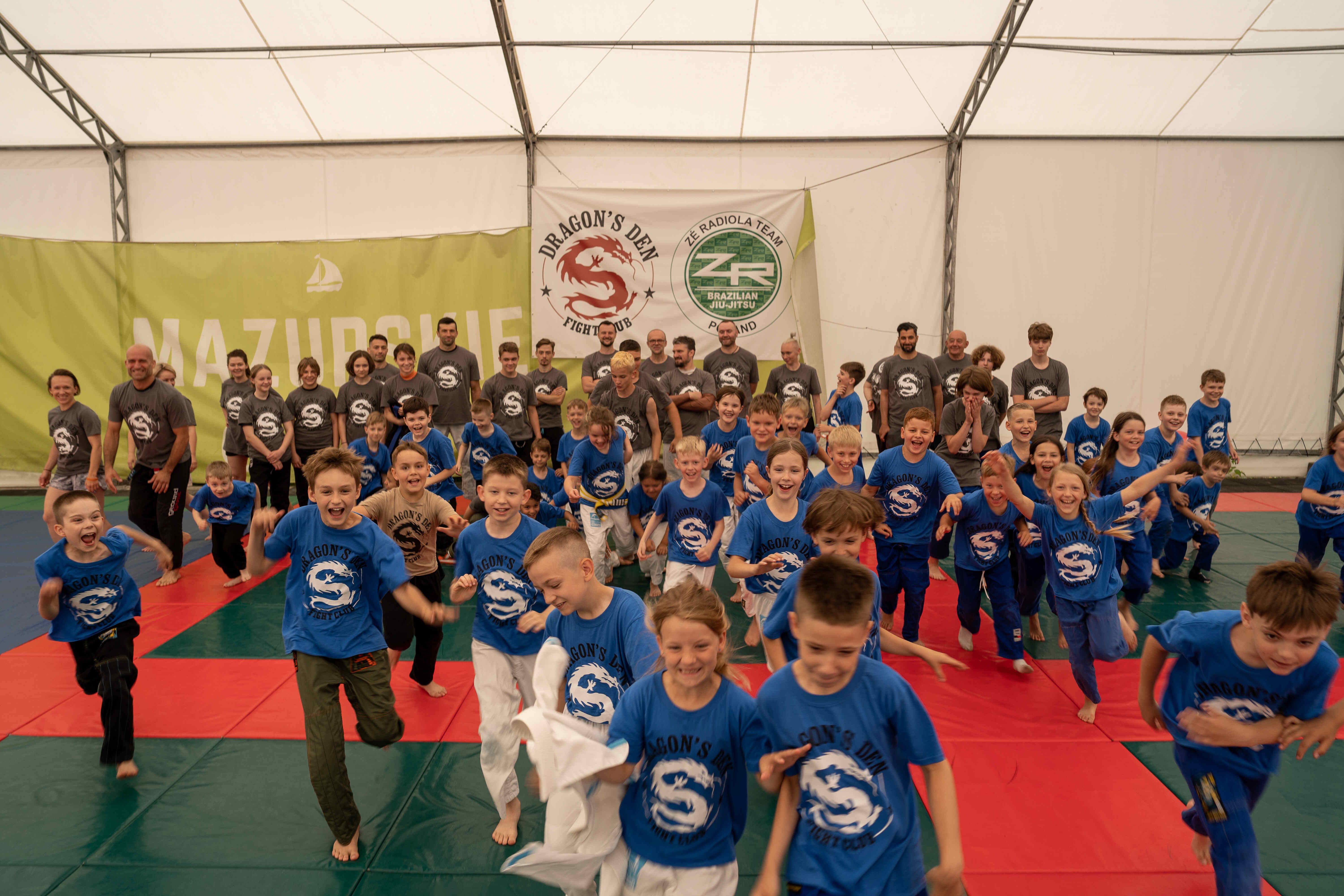 BJJ team seating at the platform holding medals and trophies