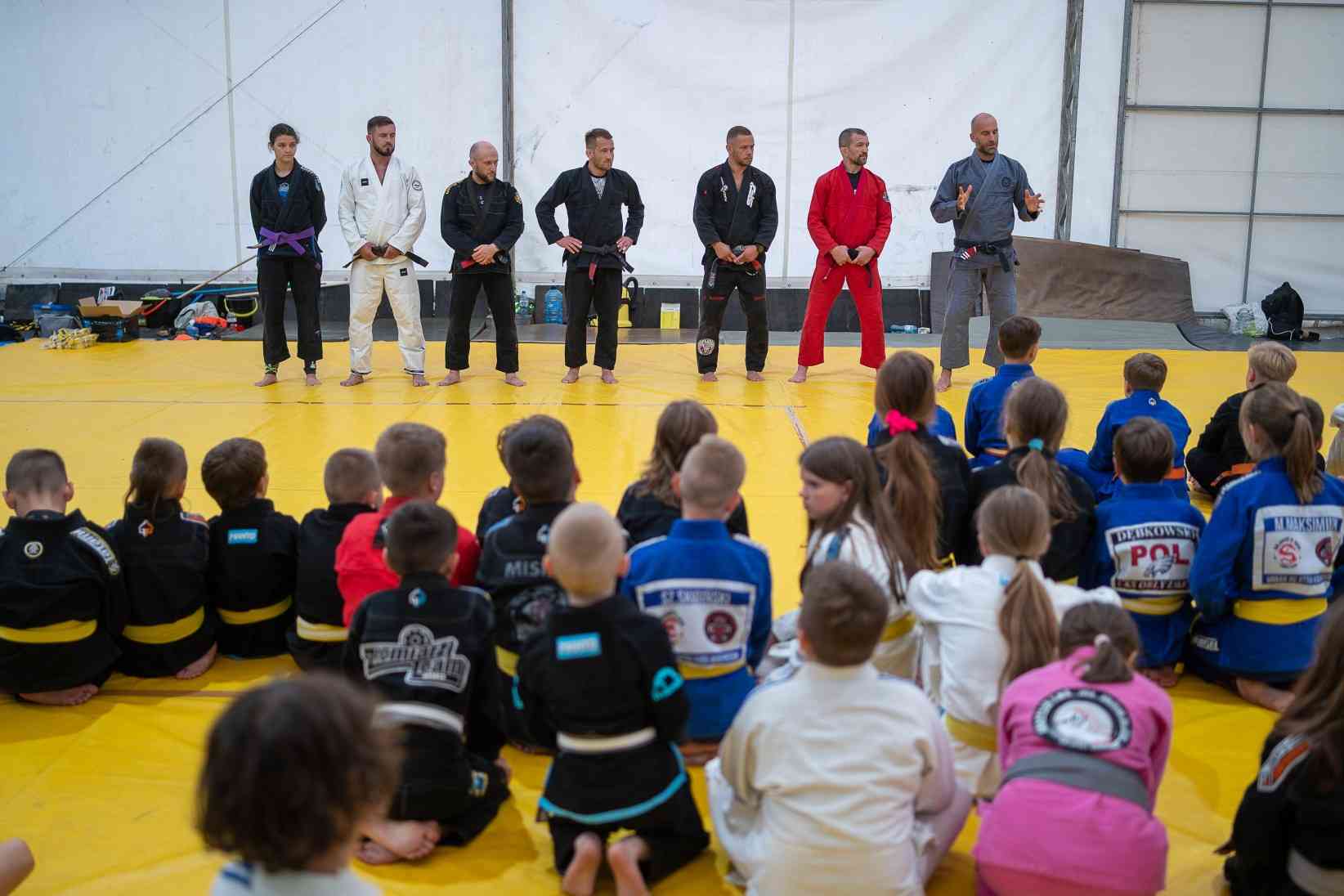 BJJ team seating at the platform holding medals and trophies